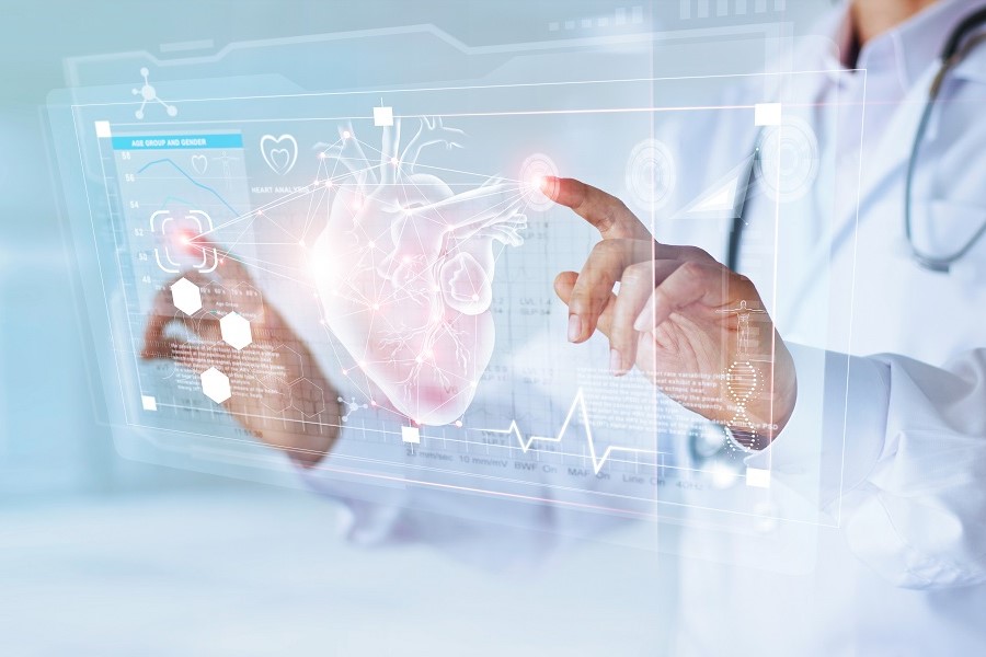 Symbolbild für Digitalisierung und KI in der Medizin, eine Person in einem weißen Kittel steht vor einer in das Bild eingeblendeten Grafik, auf dem ein Herz und Daten abgebildet sind