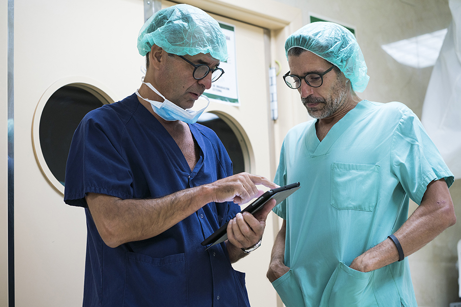 Zwei Chirurgen stehen auf Krankenhausflur und benutzen ein Tablett 