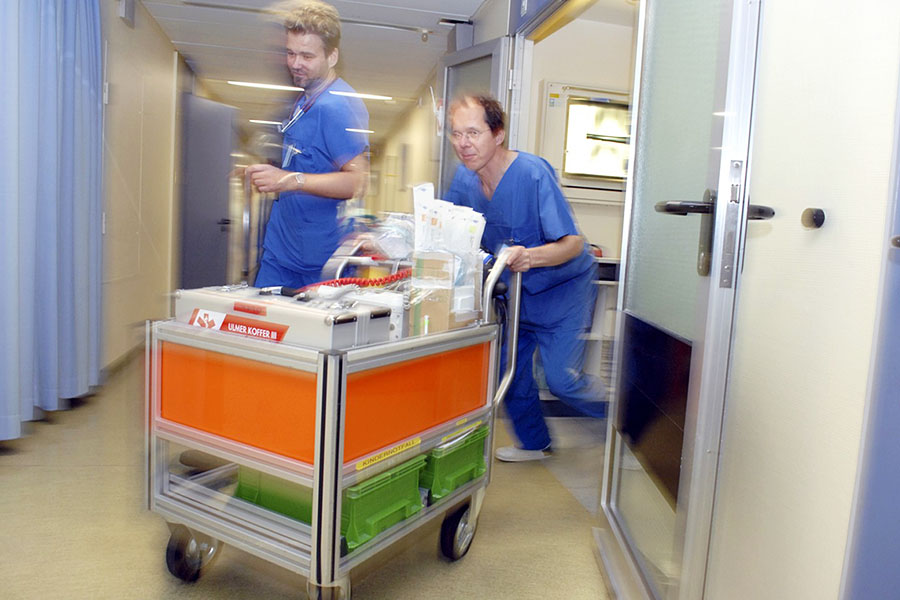 Zwei Sanitäter mit Notfallausrüstung in Bewegung.