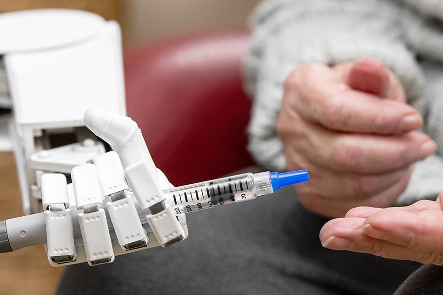 Roboterhand reicht Seniorin Insulinspritze