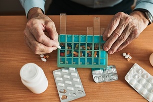 Eine Person sortiert Medikamente in eine Mehrtagesbox