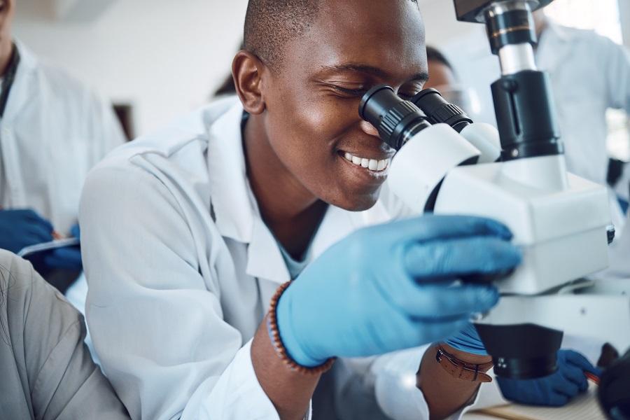 Alt-Text: Junger Arzt in Afrika schaut durch ein Mikroskop