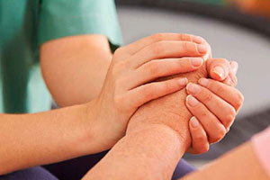 Die jungen Hände einer Pflegerin umschließen die Hand eines alten Menschen.