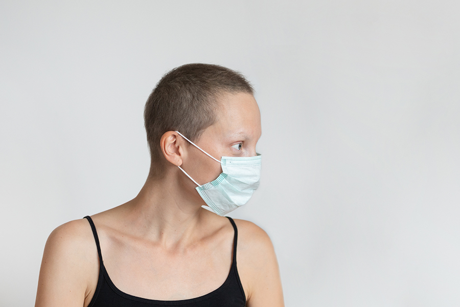 Junge Frau mit kurzen Haaren im Profil mit Atemschutzmaske 
