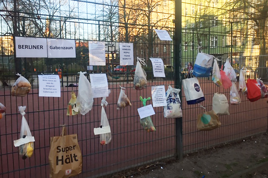 An einem Metallzaun in Berlin haben Menschen Tüten mit kleinen Spenden aufgehängt