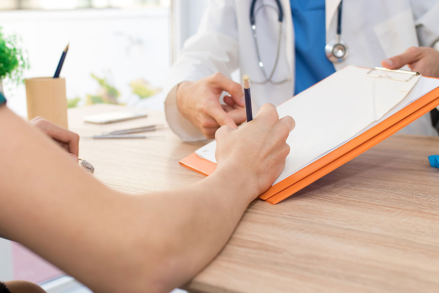 Person unterschreibt Papierbogen für Arzt