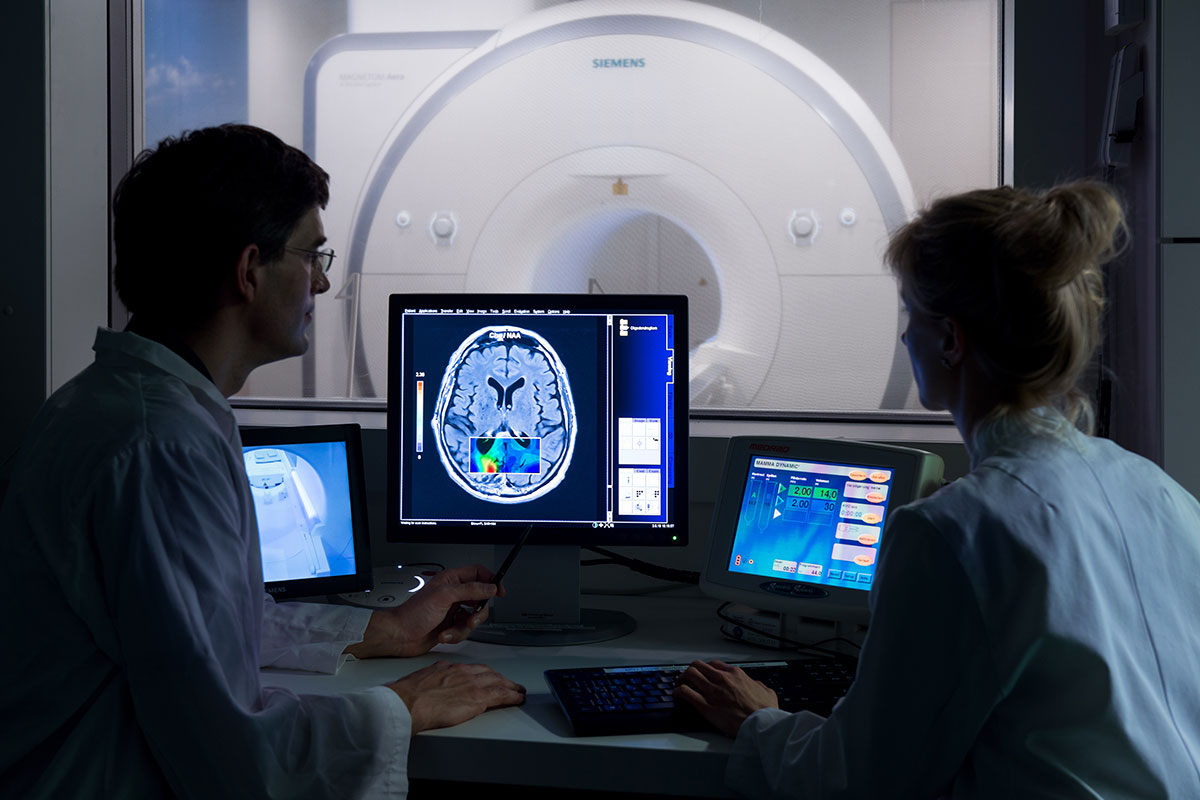 Zwei Forscher sehen sich die Ergebnisse eines MRTs am Computer an.