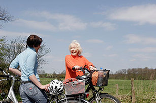 Eine ältere und eine junge Frau treffen sich mit dem Fahrrad und unterhalten sich.