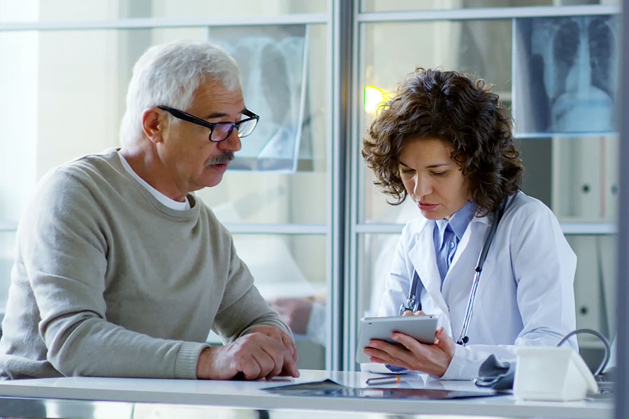 Patient und Ärztin im Gespräch, beide schauen auf das Display eines Tablet-PC.