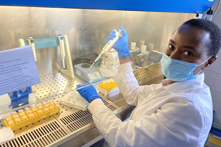 Eine junge Frau mit Mundschutz pipettiert in einem Labor