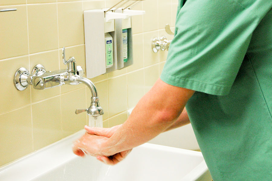 Medizinische Fachkraft wäscht sich gründlich die Hände und Unterarme.
