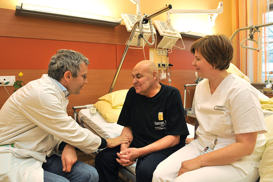 Prof. Christoph Ostgathe im Gespräch mit einem Patienten und einer Pflegerin