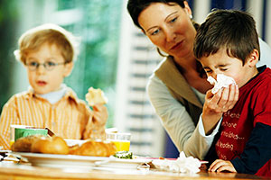 Mutter putzt Kind am Frühstückstisch die Nase