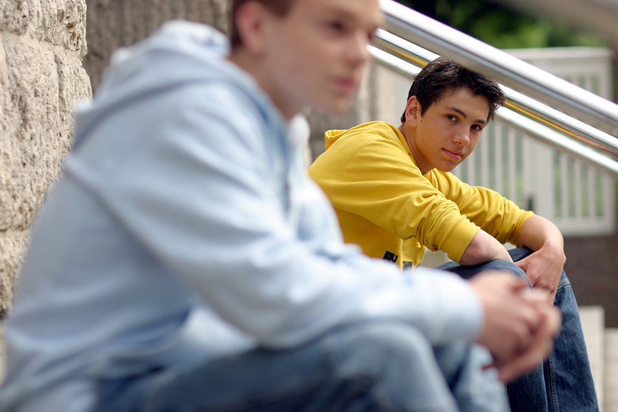 Zwei männliche Jugendliche sitzen auf Treppenstufen.