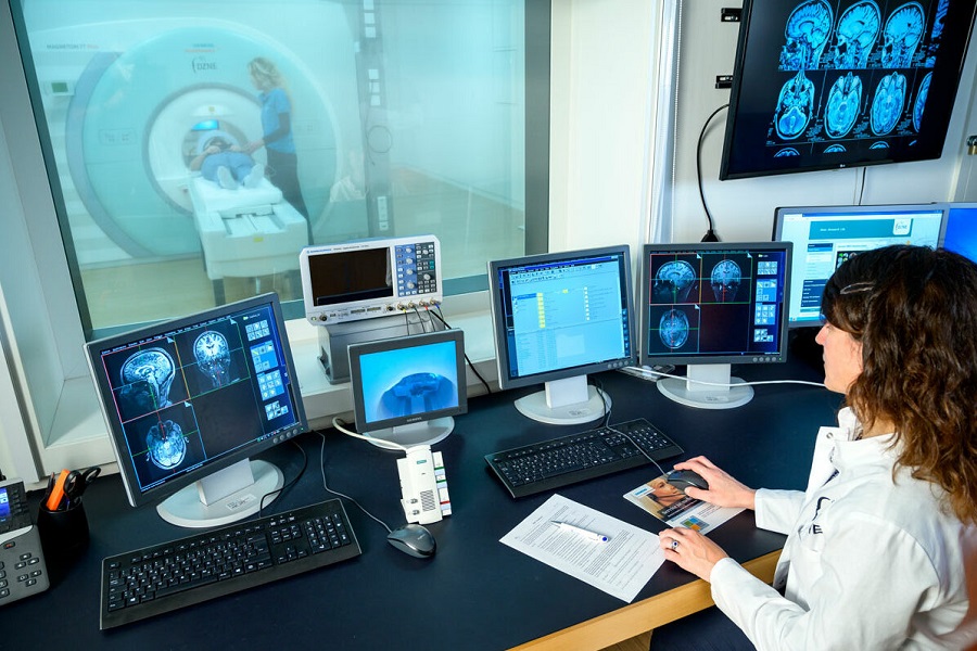 Eine Ärztin sitzt vor mehreren Computerbildschirmen und überwacht eine medizinische Untersuchung.