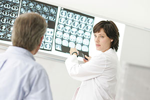 Eine Ärztin zeigt einem Patienten CT-Aufnahmen des Gehirns.