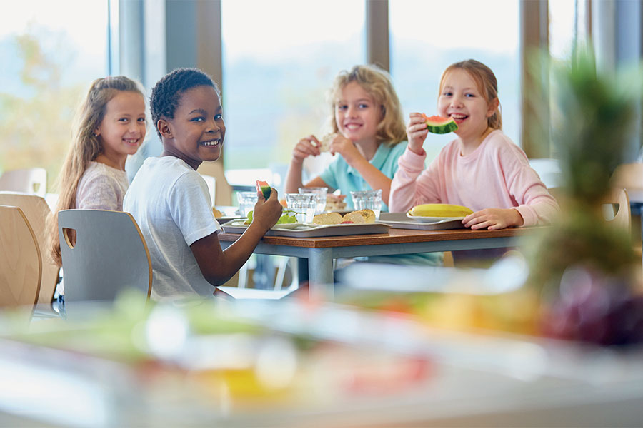 Fröhliche Kinder am Frühstückstisch mit Melone
