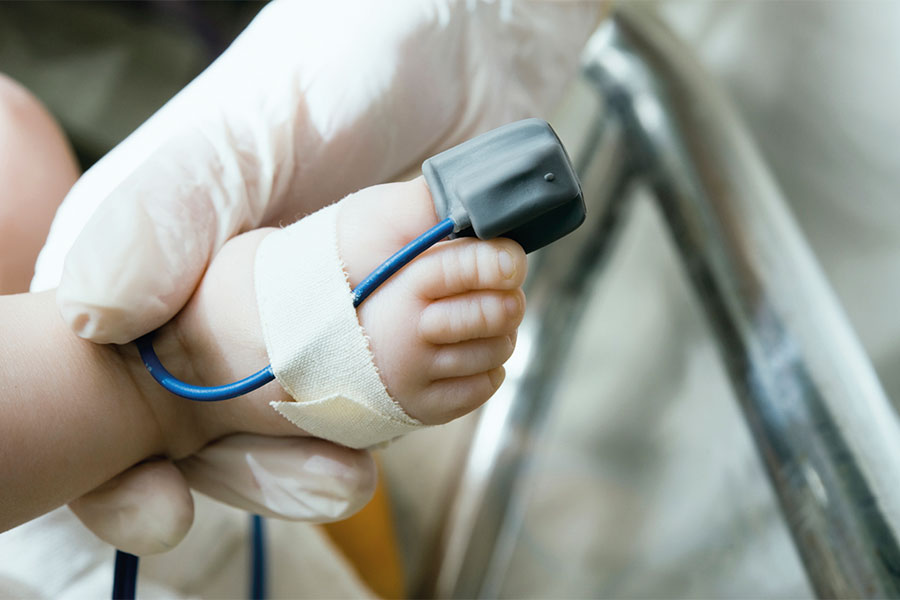 Mithilfe einer kleinen Manschette wird der Sauerstoffgehalt im Blut des Neugeborenen gemessen.