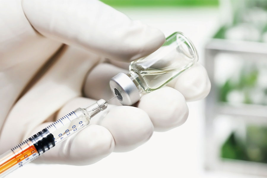Medizinische Fachkraft zieht Spritze mit Impftstoff auf.