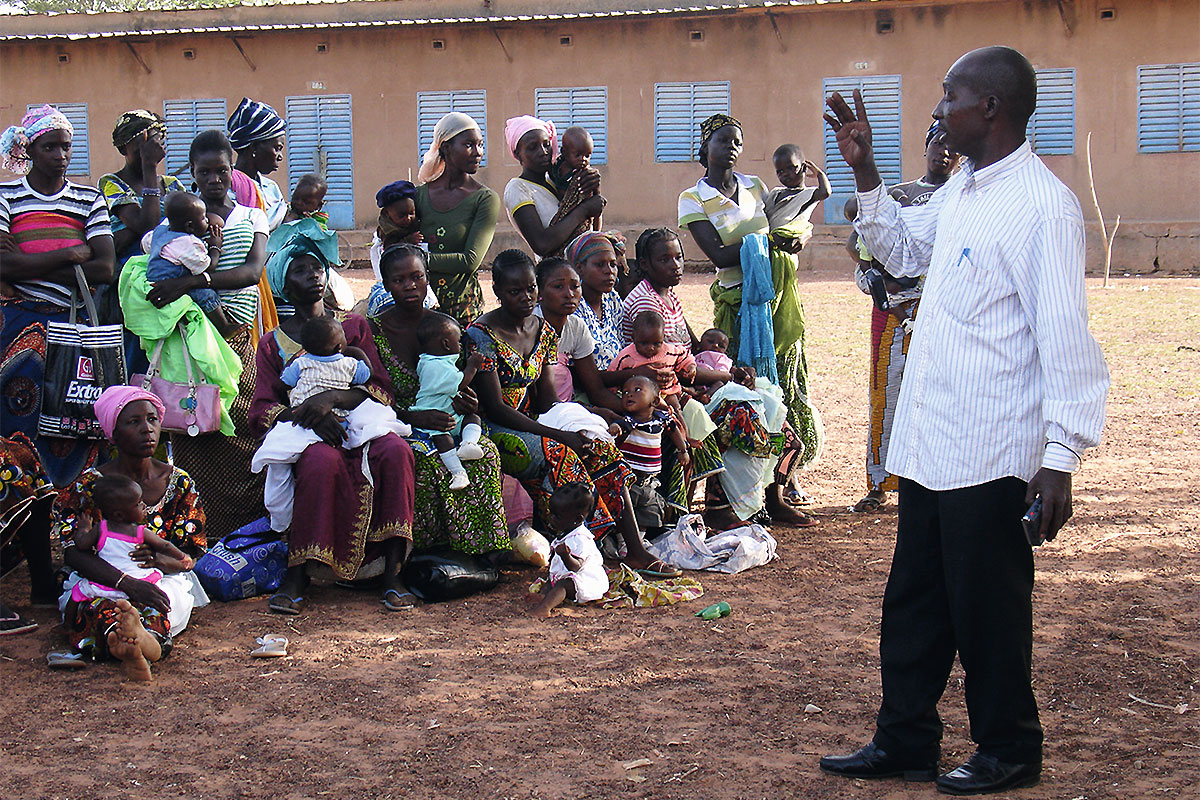 Auf einem Dorfplatz in Burkina Faso informieren sich junge Mütter über die Möglichkeit, gemeinsam mit ihren Kindern an einer klinischen Studie für einen Malaria-Impfstoff teilzunehmen.