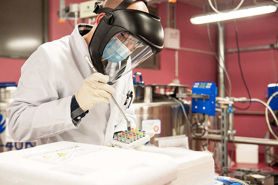Wissenschaftler im Labor hält Reagenzglas mit einer Pinzette