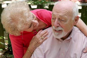 Eine ältere Dame umarmt einen älteren Herrn.