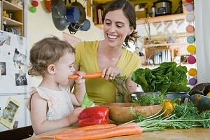 Mutter und Kind mit Gemüse in der Küche