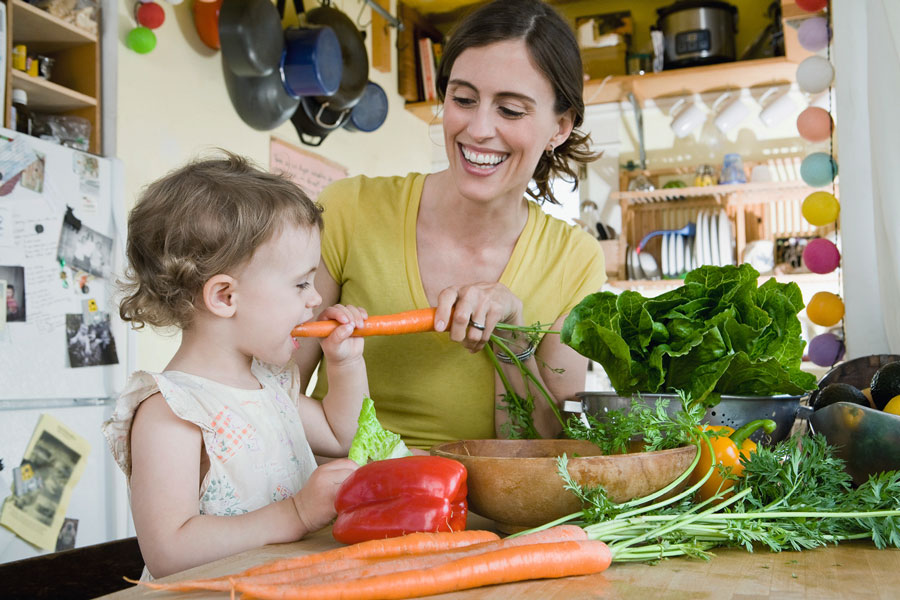 Mutter und Kleinkind mit Gemüse in der Küche