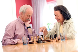 Ein älterer Mann und eine Frau spielen miteinander Schach. 