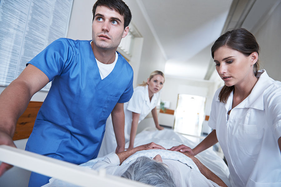 Notfallpatient wird im Bett über Klinikflur geschoben.