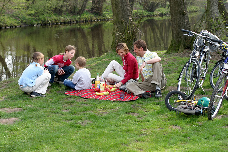 Familie macht Picknick an einem Flußufer.