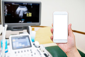 Hand hält Smartphone in einem Raum mit medizinischer Ausrüstung zur digitalen Diagnose