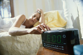 Erwachende Frau stellt ihren auf sechs Uhr gestellten Wecker aus.
