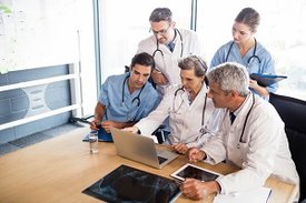 Ärztinnen und Ärzte vor Tablet-Computern tauschen sich miteinander aus