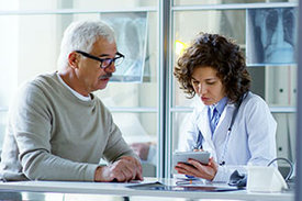 Ärztin und Patient betrachten Informationen auf Computertablet