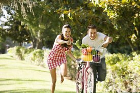 Junges Paar schiebt Fahrrad mit Gemüsekorb