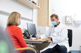 Ein Arzt und eine Patientin sitzen an einem Schreibtisch und sprechen miteinander