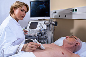 Ärztin untersucht Herz eines Patienten per Ultraschall