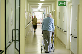 Zwei ältere Menschen in einer Pflegeeinrichtung auf dem Flur