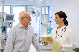 Eine Ärztin spricht mit einem Patienten in einem Operationsraum.