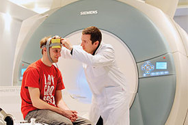 Robert Darkow, Mitarbeiter der Klinik für Neurologie mit Experimenteller Neurologie an der Charité, befestigt die Elektroden am Kopf eines gesunden Probanden, um den Einfluss der elektrischen Stimulation auf die Hirnaktivität zu messen.