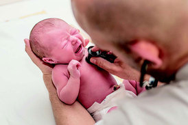 Die Lunge eines Neugeborenen wird von einem Arzt mit Hilfe eines Stethoskops untersucht. 