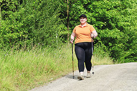 Eine übergewichtige Frau beim Nordic Walking