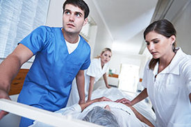 Medizinisches Fachpersonal schiebt Notfallpatienten auf einem Krankenbett durch einen Klinikflur.