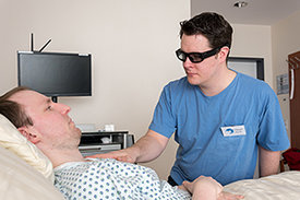 Pfleger mit Datenbrille am Bett eines Patienten