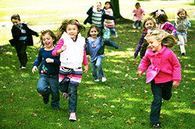 Kinder laufen über eine Wiese.
