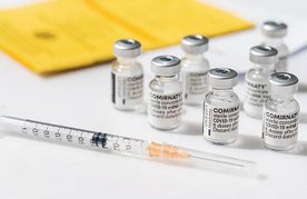 Impfstoff-Ampullen neben Impfpass und Spritze